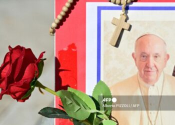 Una imagen del Papa Francisco, una rosa roja y un rosario en la estatua de Juan Pablo II afuera del Hospital Gemelli