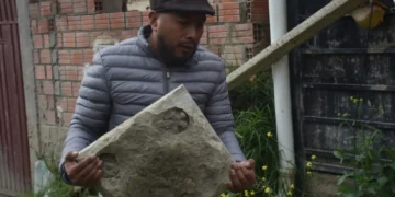 Un vecino de Bajo Llojeta sostiene en sus manos una lápida hallada entre los escombros. FOTO: GAMLP