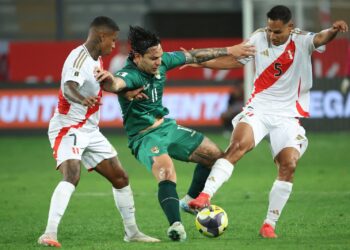 El delantero Carmelo Algarañaz soporta la marca de dos rivales peruanos.