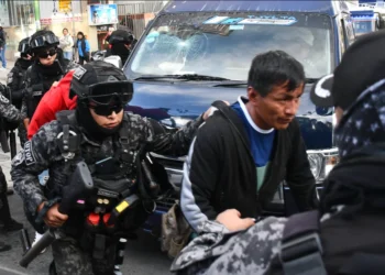 Un agente policial conduce a uno de los aprehendidos hasta la FELCC. (Foto APG)