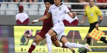 El zaguero boliviano Efraín Morales se anticipa a un rival venezolano.