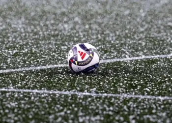 El balón del partido en el césped cubierto por el granizo