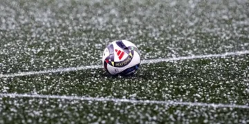 El balón del partido en el césped cubierto por el granizo