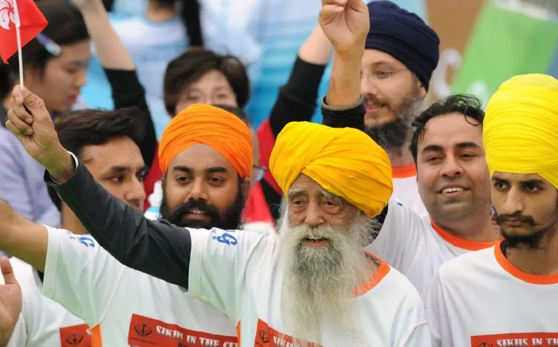Fauja Singh saluda con un banderín tras finalizar una carrera en Hong Kong. (FOTO: AFP)
