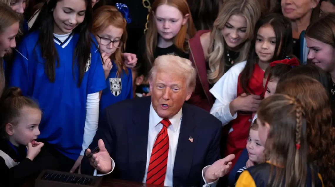 Donald Trump, en la sala Este de la Casa Blanca, con niñas, adolescentes y mujeres detrás, en el acto de firma del decreto. (FOTO: AFP)