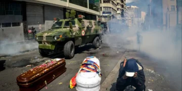 Un carro blindado avanza entre ataúdes y humo de gases lacrimógenos durante una protesta en La Paz, tras la masacre de Senkata en 2019.