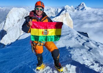 Hugo Ayaviri en la cima de la montaña, con la bandera de Bolivia.