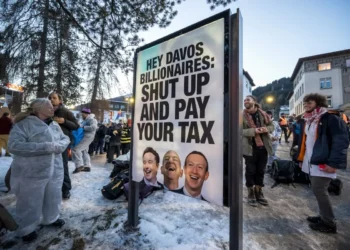 Una pancarta con los retratos de Elon Musk, Jeff Bezos y Mark Zuckerberg en una protesta en Davos/AFP