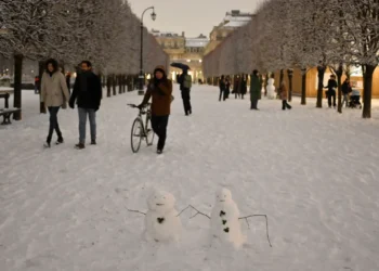 Los peatones pasan junto a pequeños muñecos de nieve en el Palacio Real cubierto de nieve en París