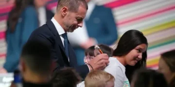 El presidente de la UEFA, Aleksander Ceferin, le firma una camiseta a una niña durante el Congreso Ordinario del organismo. (FOTO: AFP)