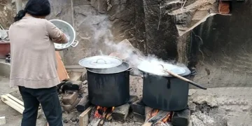 Una mujer cocina a leña.