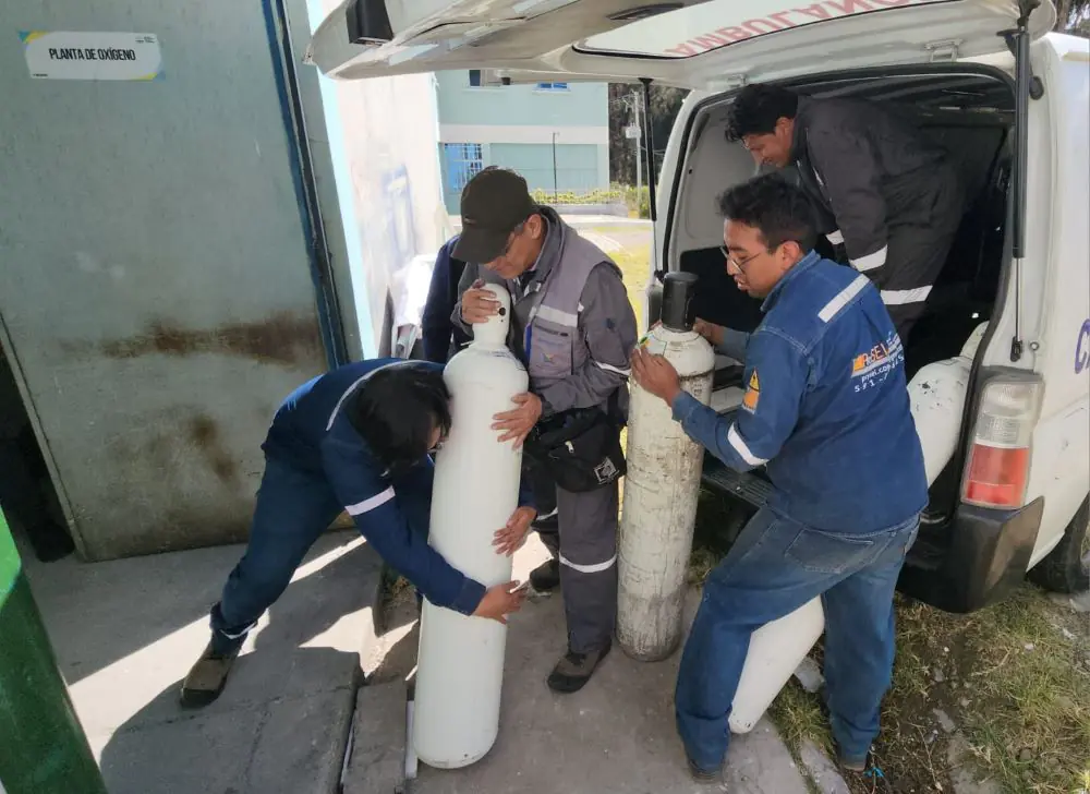 Trabajadores de la UMSA cargan los botellones de oxígeno medicinal. FOTO: UMSA
